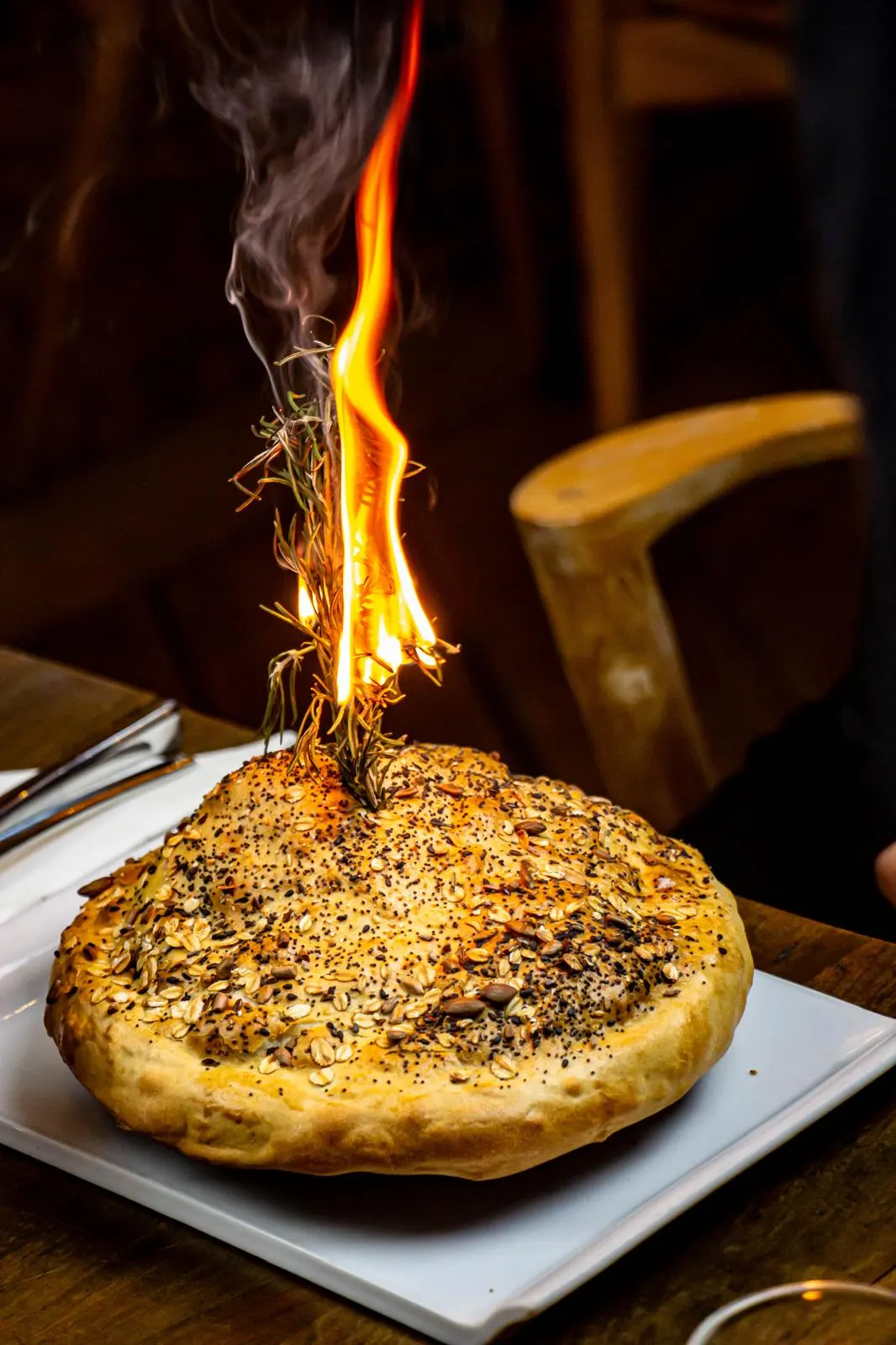 Pain maison aux graines servi avec un brin de romarin flambé