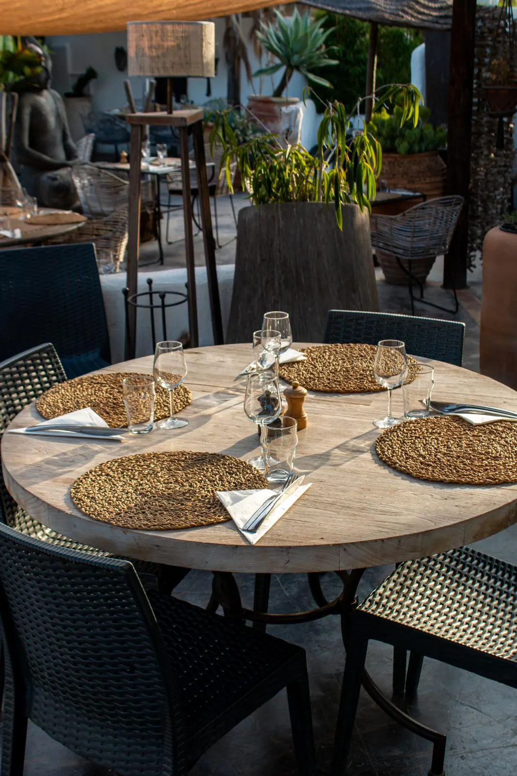 Table ronde dressée sur la terrasse de Nomade, sets tressés et verres